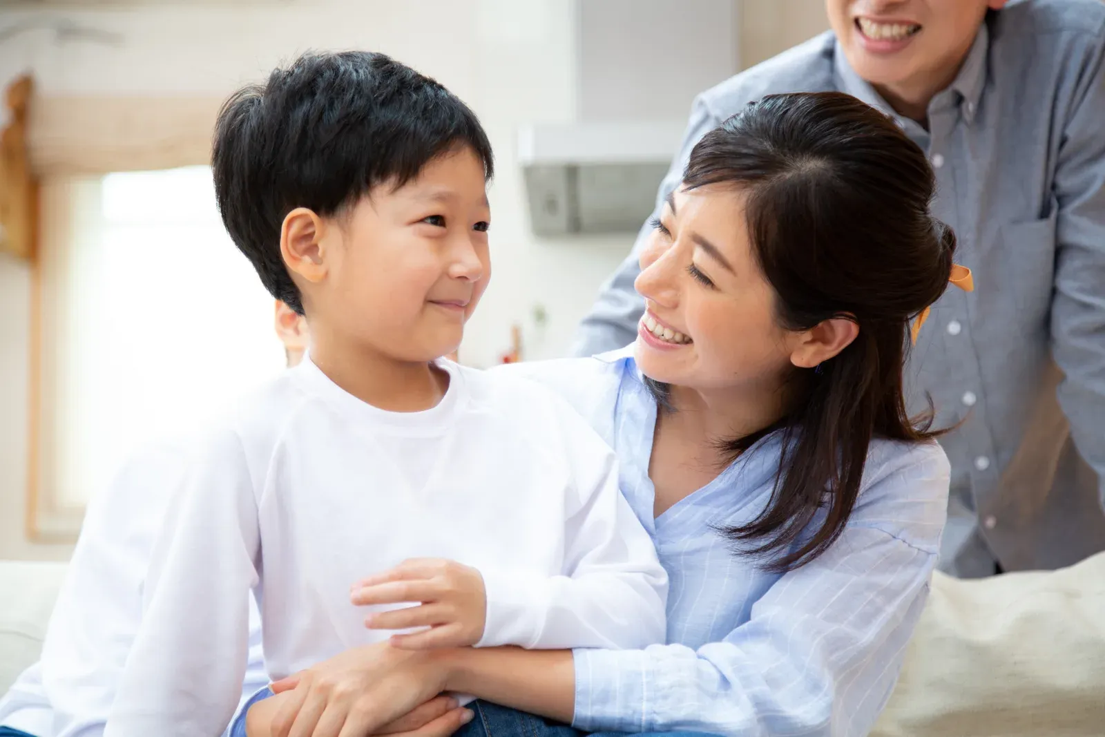 親子が笑顔で目線を合わせ、子どもを抱きしめている温かいワンシーン