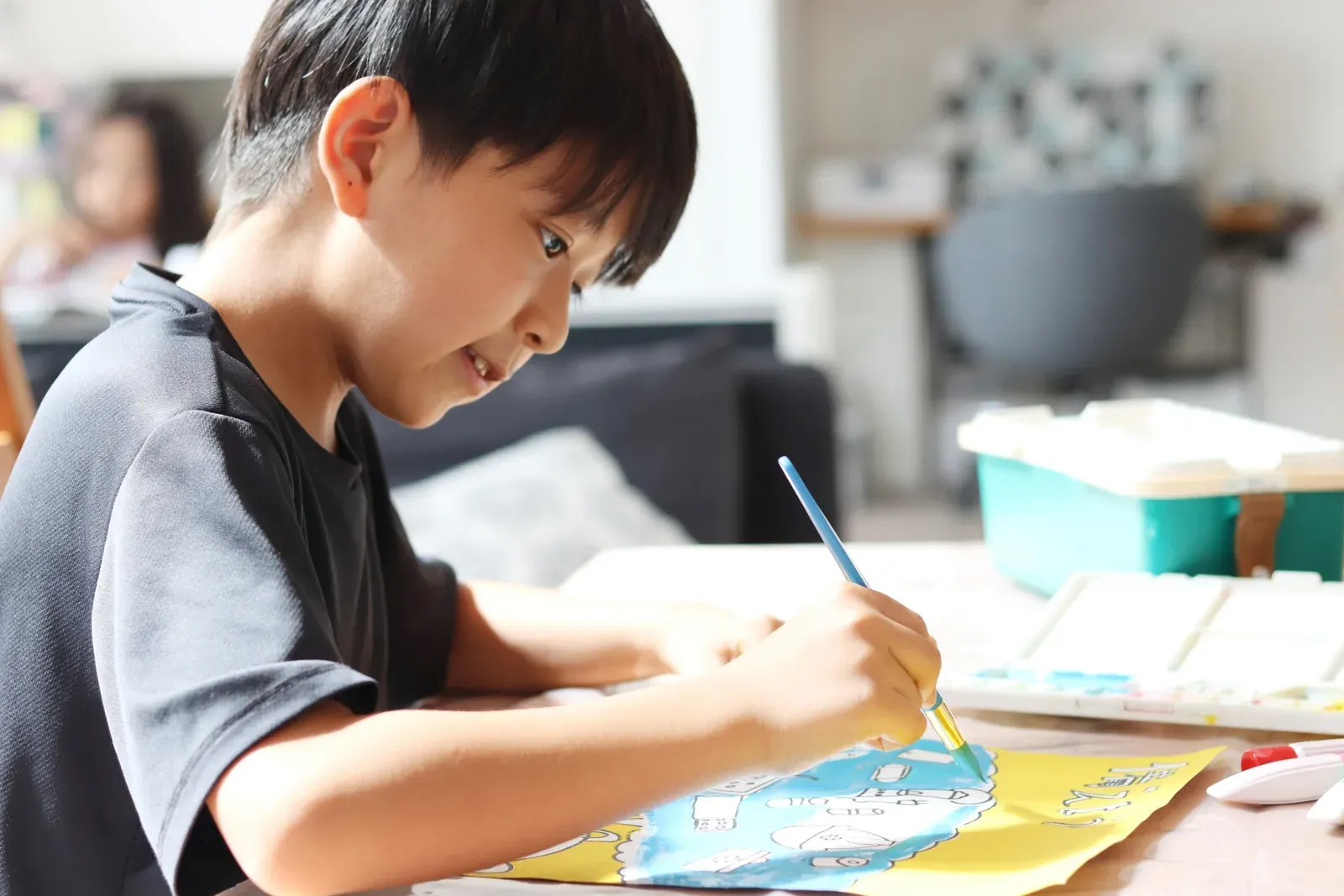 子どもが筆を使って夢中で絵を描いている横顔